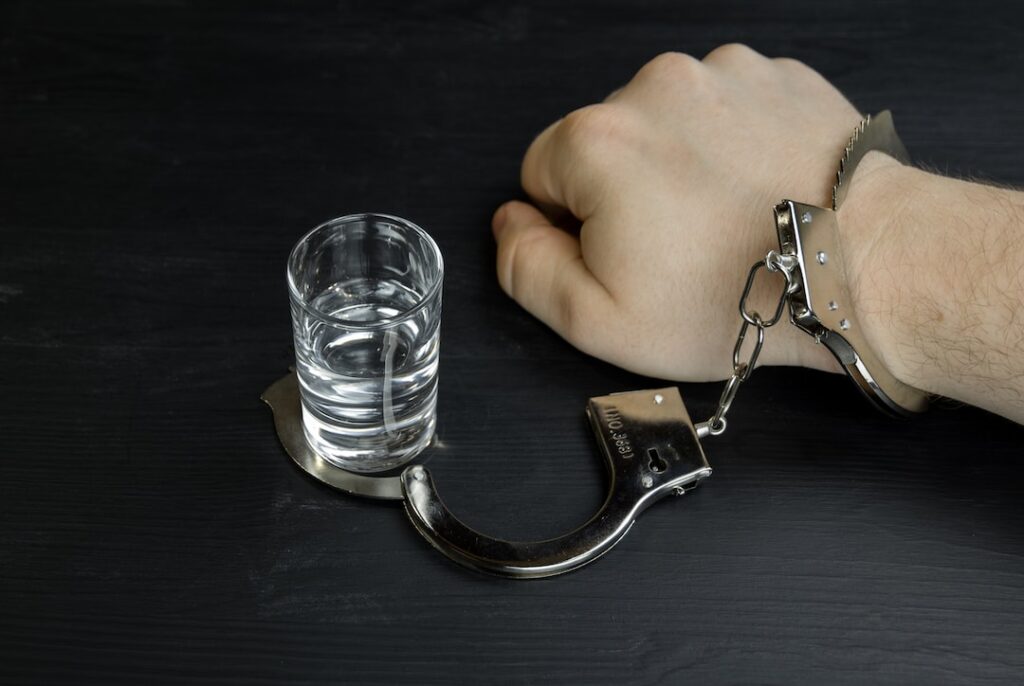a hand with handcuffs on a glass of water